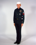 Navy Enlisted E6 & Below Winter Service Blue Uniform worn with white Dixie Cup cover, black neck tie, ribbons and badges.