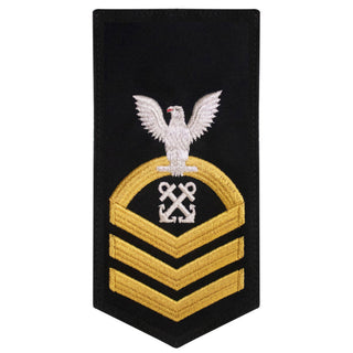 USN Male Rating Badge: E-7 Boatswains Mate (BM) - Standard Seaworthy Gold on Blue for Service Dress & Dinner Dress Blue uniform. Gold chevrons indicate 12 years of consecutive good conduct.  - CPO embroidered Regulation Gold Chevron on Blue with White Eagle and Designator.  - Gold & White Embroidery on Dark Blue Polyester Wool. - US Navy Certified - Made in the USA