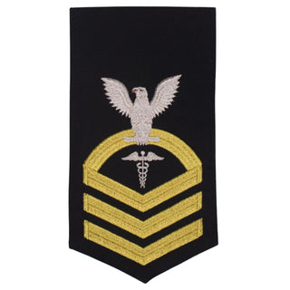 USN Male Rating Badge: E-7 Hospital Corpsman (HM) - Standard Seaworthy Gold on Blue for Service Dress & Dinner Dress Blue uniform. Gold chevrons indicate 12 years of consecutive good conduct.  - CPO embroidered Regulation Gold Chevron on Blue with White Eagle and Designator.  - Gold & White Embroidery on Dark Blue Polyester Wool. - US Navy Certified - Made in the USA